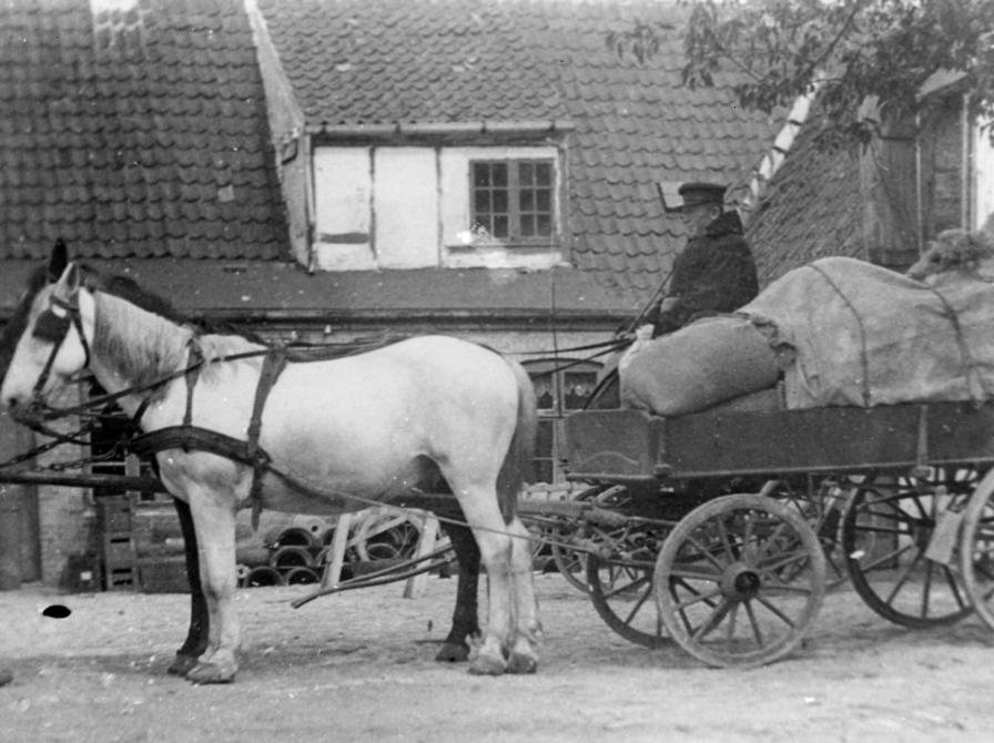 Lars Roed var født 1866 i Sæby, i en tid hvor landets styre blev mere elitært. Her ses han til vogns med pakket læs holdende på gårdspladsen i Brdr. Lützhøft's købmandsgård i Ringstedgade 6-8 i Roskilde